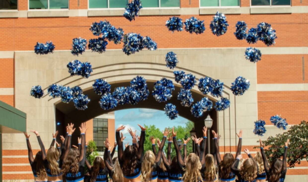 Dance team throws pom-poms towards the sky in celebration